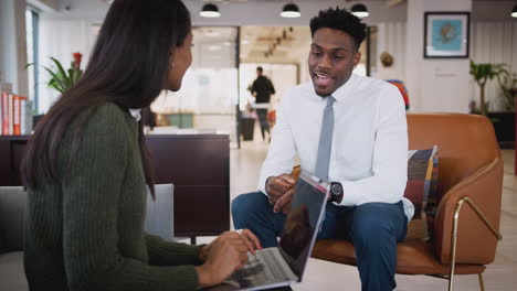 businesswoman interviewing male job candidate in seating area of modern office