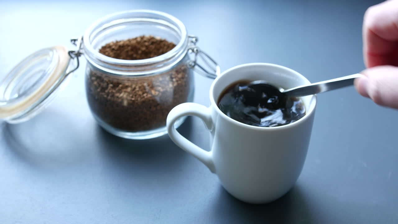 아침에 부엌에서 아침에 김이 나는 뜨거운 커피를 휘젓다