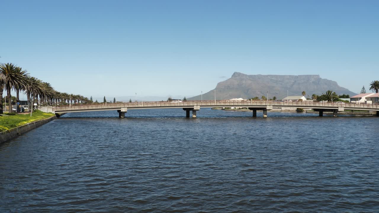 자동차 교통이 낮은 다리를 건너면서 야자수가 해안가 거리에 늘어서 있습니다.