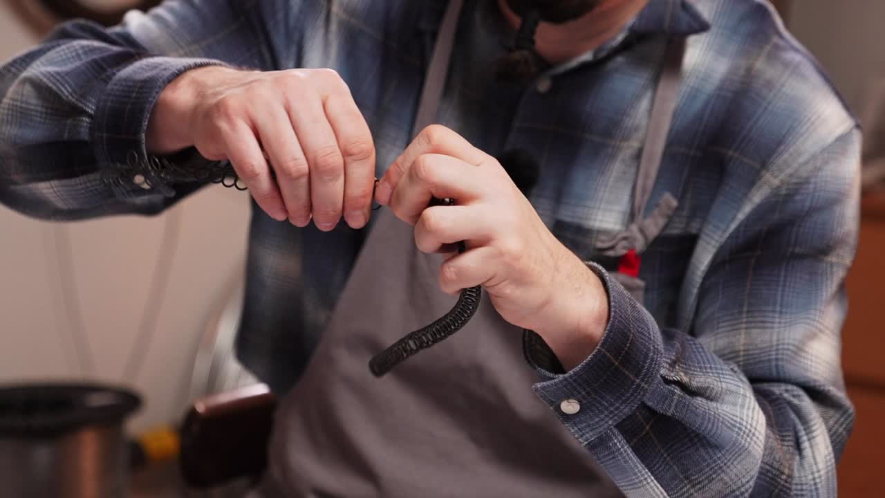 Medium close up of craftsman shaping decorative metal wire by hand in workshop. Traditional Slovak wire craft technique, drotarstvo folk art and handmade craftsmanship