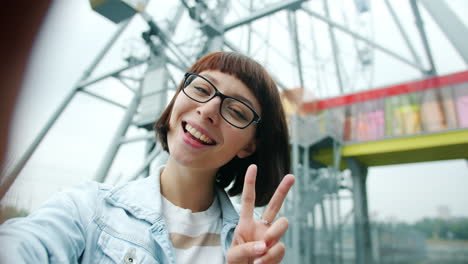 smiling woman taking a selfie near a ferris wheel