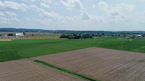 An-Aerial,-Slow-Rotation,-of-Farmlands,-With-Green-Fields-and-Plowed-Fields-on-a-Partially-Sunny-Day