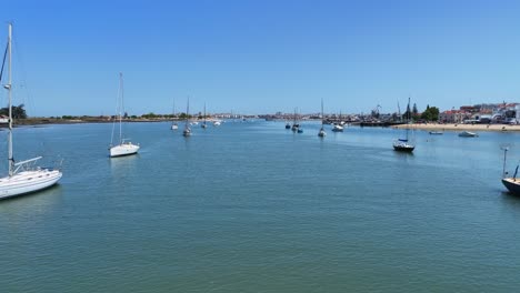 drone disparado volando bajo sobre el agua con barcos de vela anclados