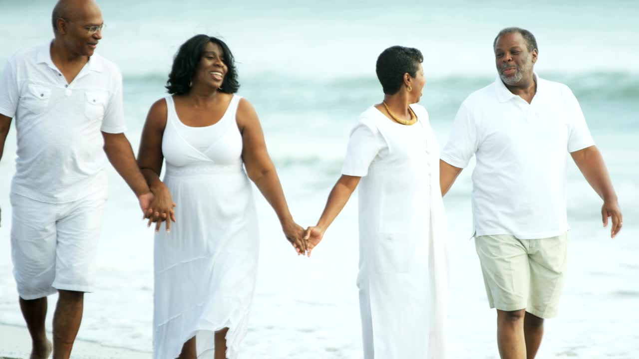 Amis afro-américains seniors appréciant une promenade sur la plage