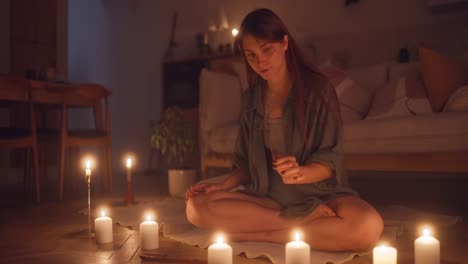 woman meditating with candles at night