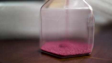 macro shot of pink sand particles in hourglass sand timer clock