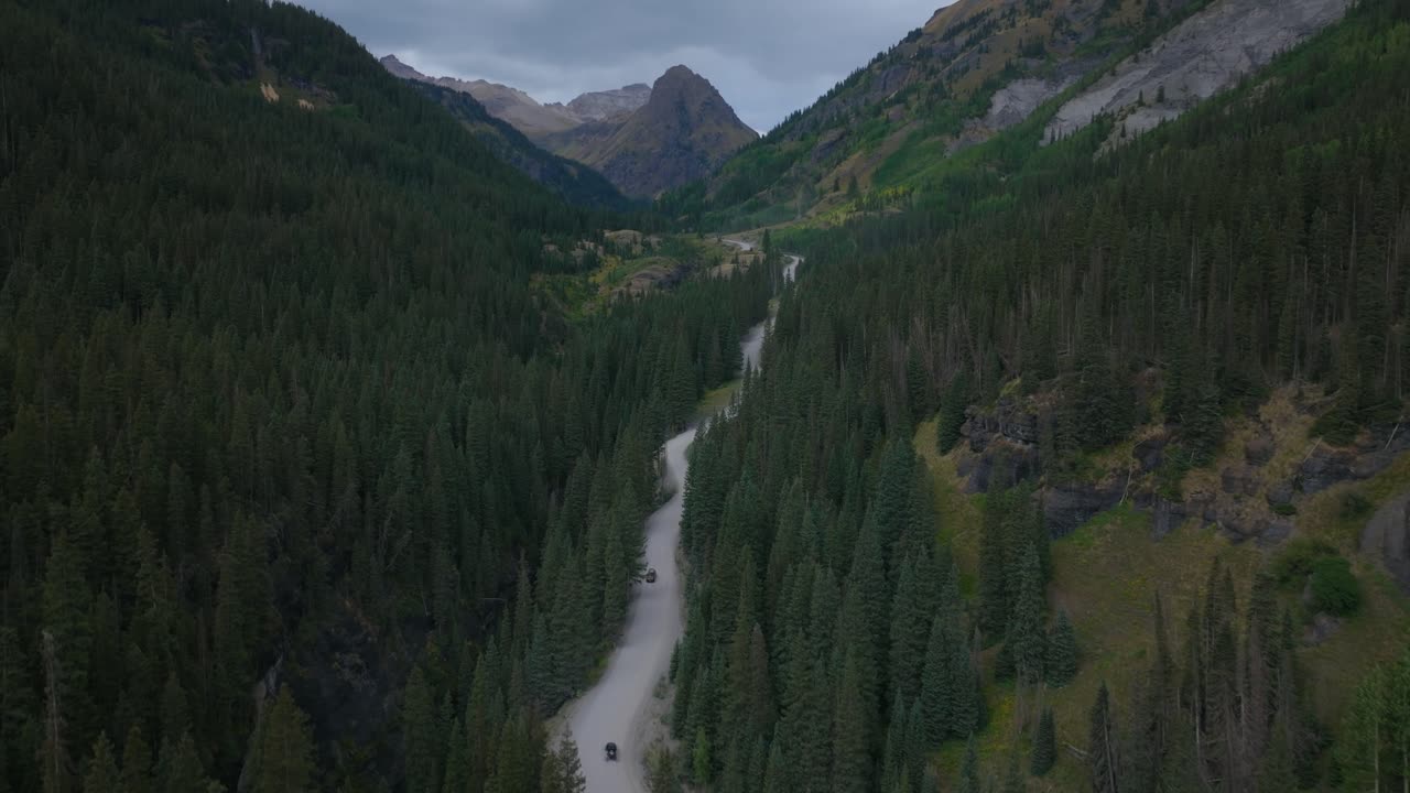 Fjellvei i en alpedal slynger seg gjennom tett skog, luftopptak med oppstigende sirkelbevegelse, Yankee Boy Basin Ouray Colorado USA