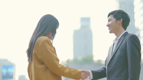 panning shot. business partners or business people meeting and shake hands in business district. handshake between colleagues man and woman working together. young entrepreneurs shaking hands greeting.