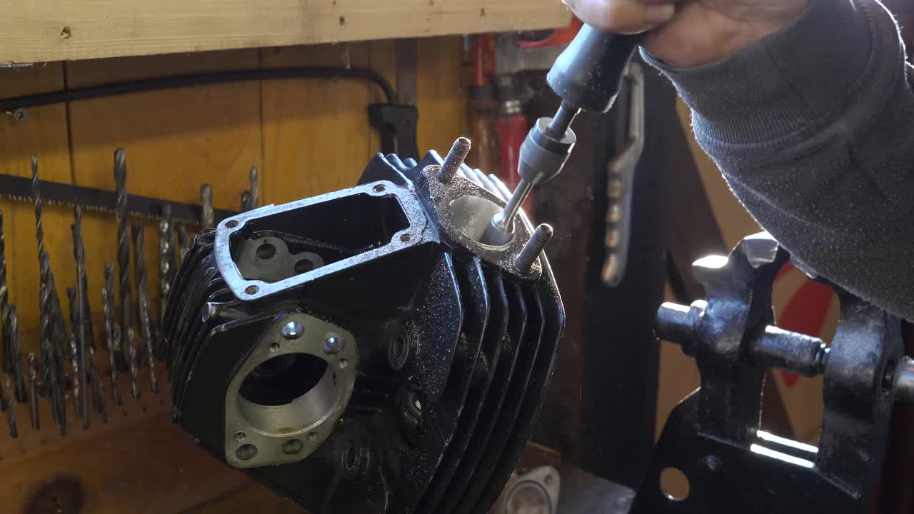 trabajador caucásico utiliza herramienta de afilado para trabajar en un bloque de motor, detalle de la mano
