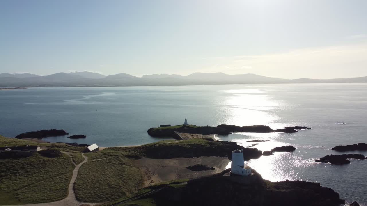 태양이 떠오르는 아일랜드 해를 가로질러 흐릿한 스노우도니아 산맥과 함께 이랜드드윈 섬을 공전하는 공중 전망
