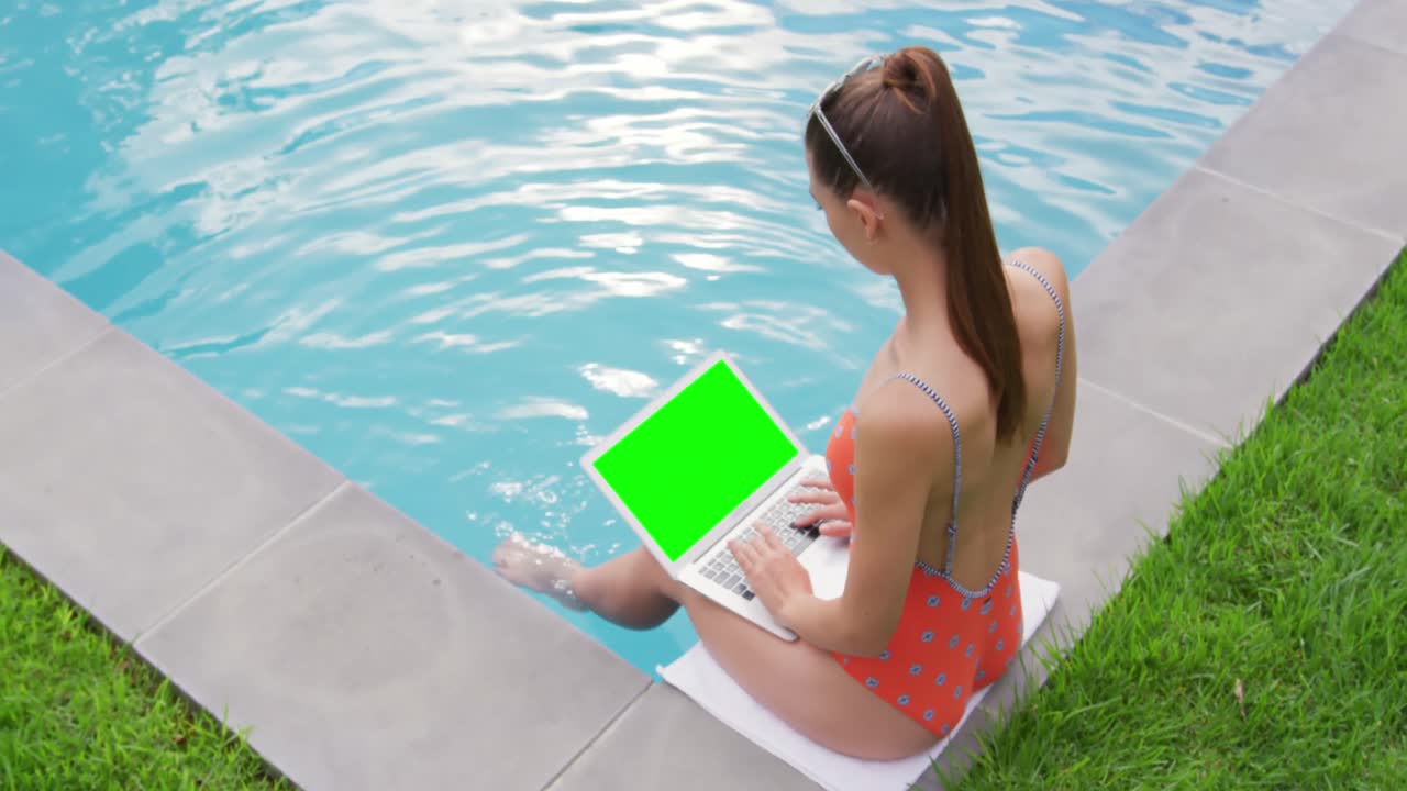 Woman using laptop near swimming pool in the backyard 4k
