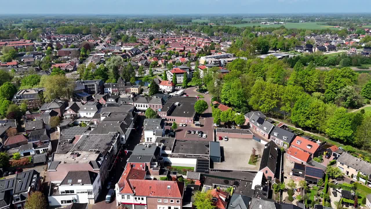 Quiet dutch neighborhood during sunny day with green trees in spring. Aerial forward wide shot. Historic row of houses and homes. Bright sky in The Netherlands.