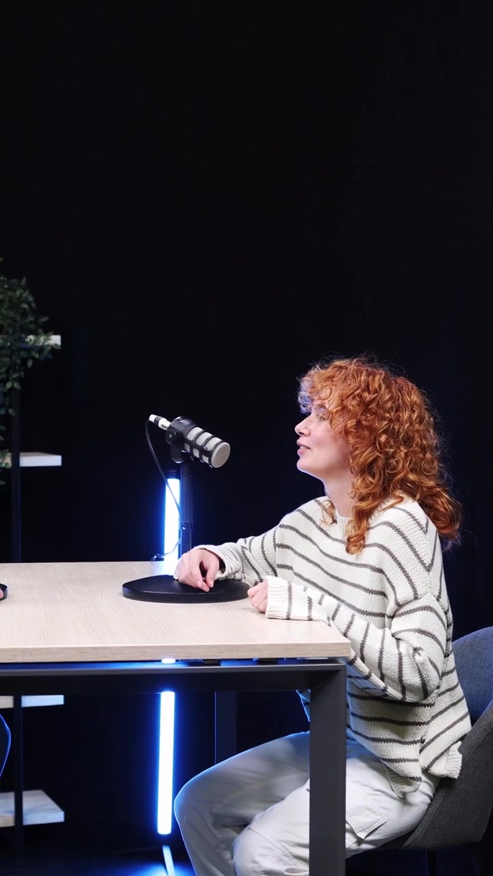 Kvinde giver hånd og sætter sig til et podcastinterview