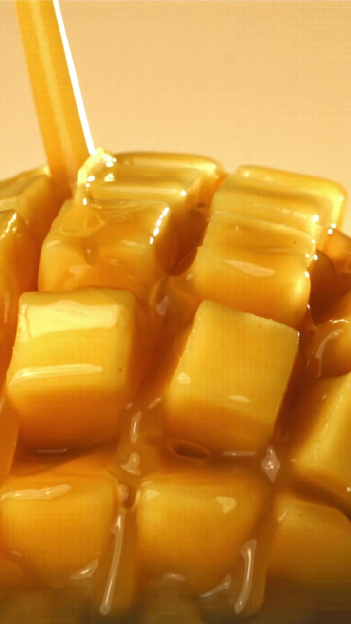 Sciroppo dorato dolce che cola su mango fresco a cubetti