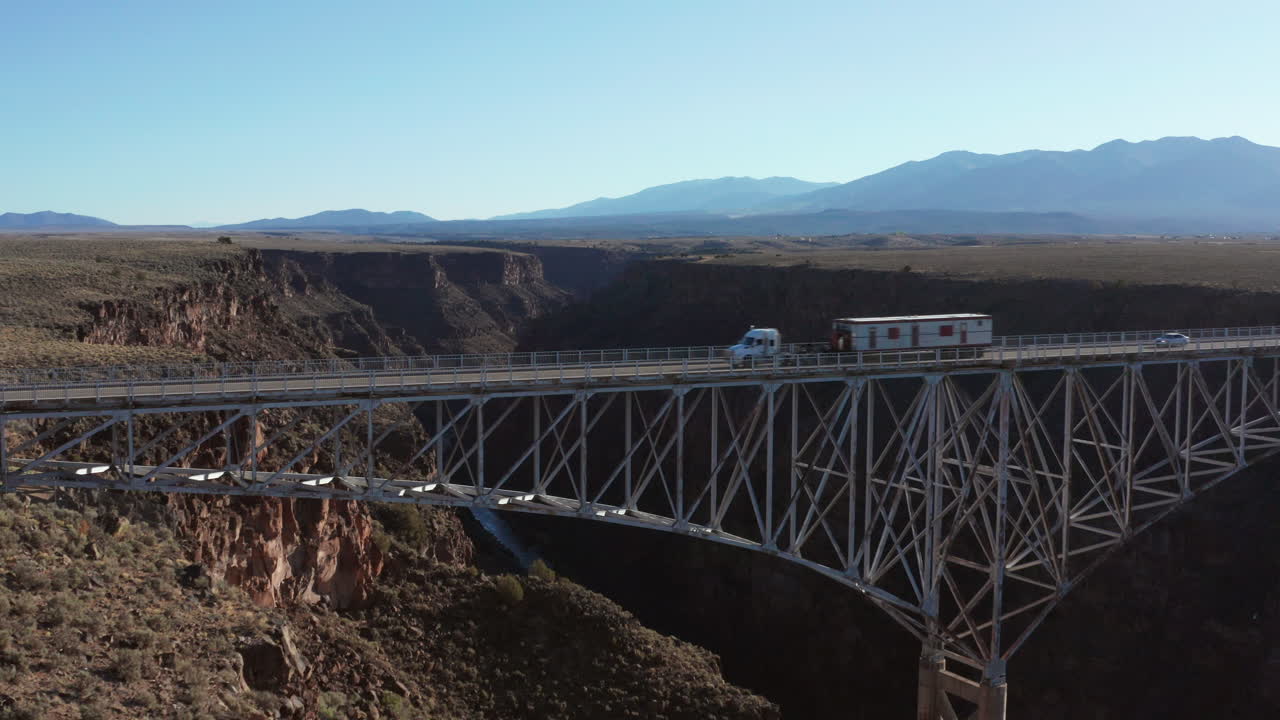 큰 사막의 강 협곡을 가로지르는 경치 좋은 다리를 지나가는 세미 트럭