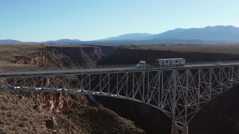 semi camión pasando por un puente panorámico que atraviesa un gran desfiladero del río del desierto