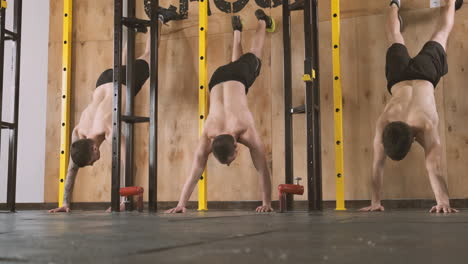 Three-Young-Athletic-Men-Doing-Abdominal-Exercises-And-Climbing-A-Wall-With-Their-Feet-In-The-Gym
