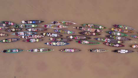 colorful boats on brown river getting pulled by motorboat, floating market, top down