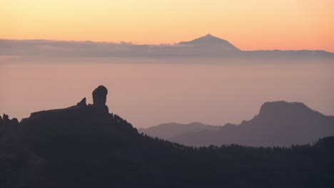 stunning sunset timelapse of roque nublo and teide emerging from the mist. golden sky, mountain silhouettes, and tranquil vibes. perfect for travel, nature, adventure, and scenic projects