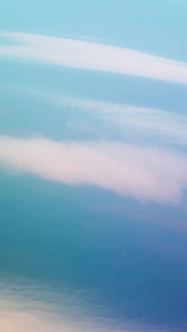 Vertical view of soft pastel clouds and blue sky from above, capturing a calm atmospheric scene with smooth gradients and tranquil light.