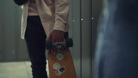 boy hand holding skateboard with stickers in school hall close up. hobby concept