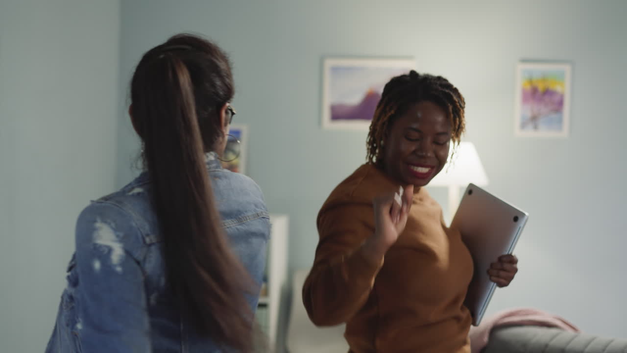Cheerful women enjoy dancing holding laptop and textbook