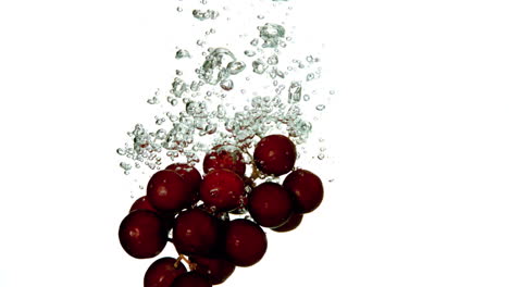 grapes falling in water on white background