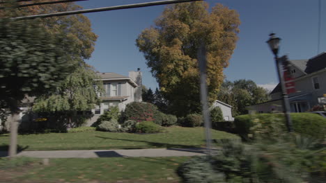 drive along a typical street of an american town on a clear autumn day. side view