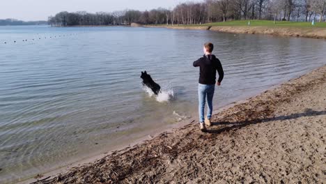 guy and his pet dog playing fetch in the water