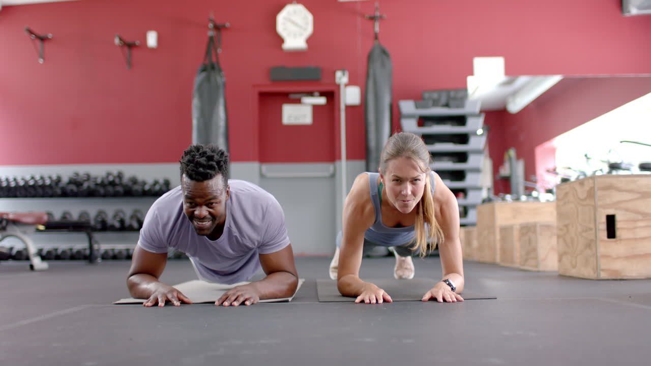 una pareja diversa haciendo tablas en el gimnasio