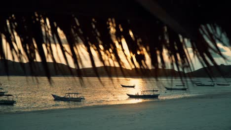 tracking shot of boats on sandy beach at sunset in indonesia