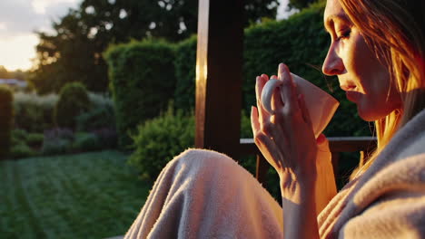 woman enjoying a drink on a porch at sunset