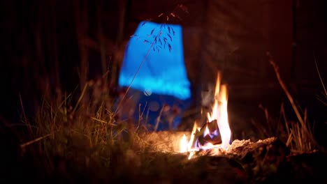 cerca del fuego ardiendo fuera de la tienda de campaña por la noche