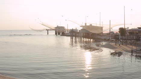 Paisaje-De-Cabañas-De-Pesca-En-El-Río-Al-Amanecer-Con-La-Típica-Máquina-De-Pesca-Italiana,-Llamada-&quot;&quot;trabucco&quot;&quot;,lido-Di-Dante,-Fiumi-Uniti-Ravenna-Cerca-Del-Valle-De-Comacchio