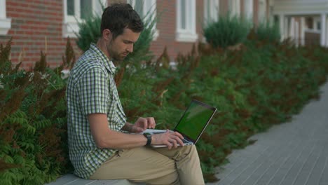 hombre trabajando en una computadora portátil al aire libre en un banco