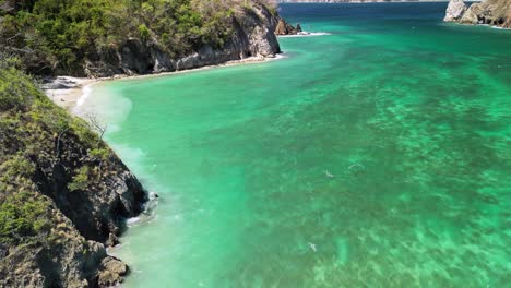 Aerial-landscape-pan-shot-of-the-clear-water-beach-in-Tortuga-Island,-Costa-Rica