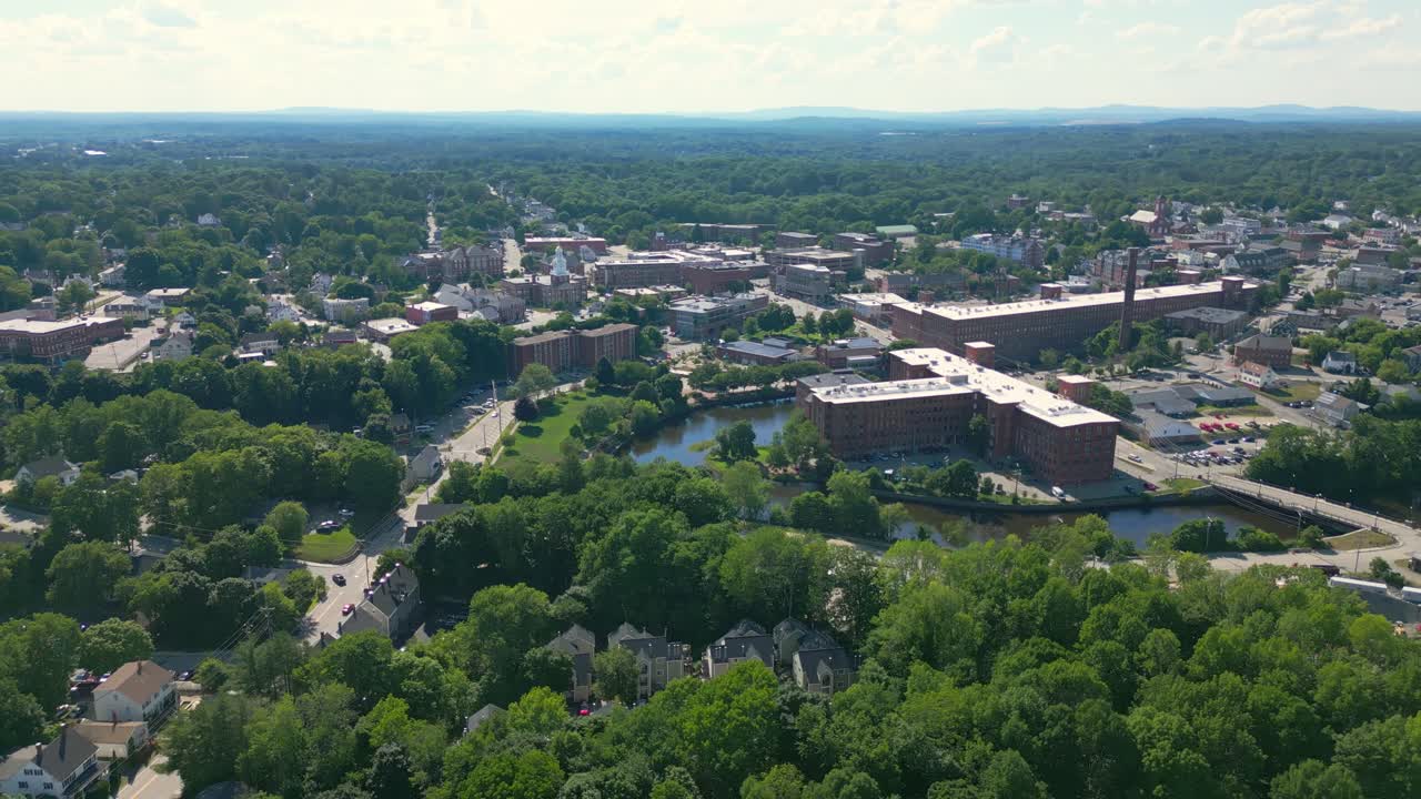 Orbita lenta con drone del centro storico di Dover, NH, USA. È una luminosa e soleggiata giornata estiva e mostra il fiume, l'antico mulino e il municipio. Mostra anche le montagne in lontananza