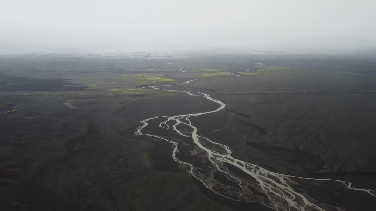 río a través de paisaje de arena negra en la niebla en islandia