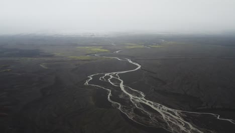 Río-A-Través-Del-Paisaje-De-Arena-Negra-En-La-Niebla-En-Islandia