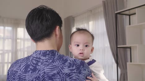 asian father holding his son at home