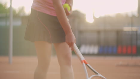 close-up of a woman picking up a ball from the ground on the map using a racket. close - up of a tennis ball