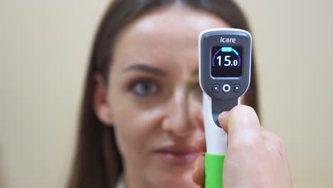 Special ophthalmic device for eyesight check applied to a patient. Doctor holds the medical gadget in front of a woman's eye.