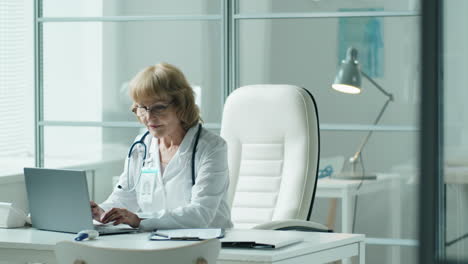 female doctor using laptop and taking notes in medical office