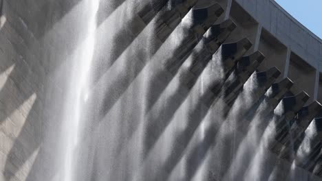 artistic backlit water falls like rain from hydro dam wall flood gates