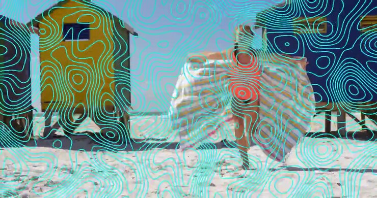 Girl walking past bright beach cabins opening striped towel revealing red swimsuit for fashion ad