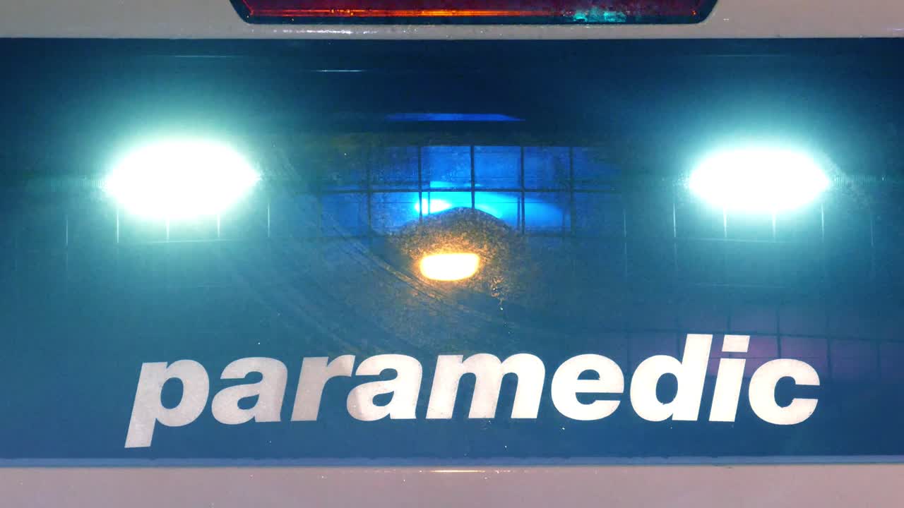 사고 현장에서 구급차 뒷창문에 비상등이 번쩍이고 있다