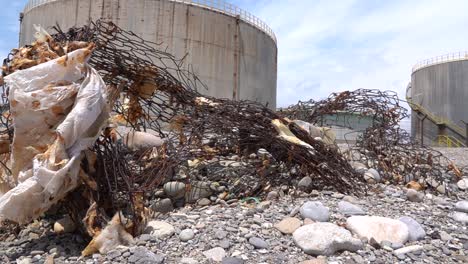 pollution on the beach, rusty fence with industrial buildings