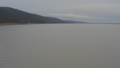 Un-Dron-Vuela-Sobre-El-Lago-George-En-Dirección-A-La-Autopista-Cerca-De-Canberra-En-Un-Día-Nublado-De-Invierno