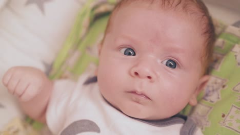 newborn-baby-in-bodysuit-lies-in-cocoon-in-bedroom-closeup