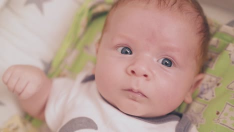 newborn baby in bodysuit lies in cocoon in bedroom closeup